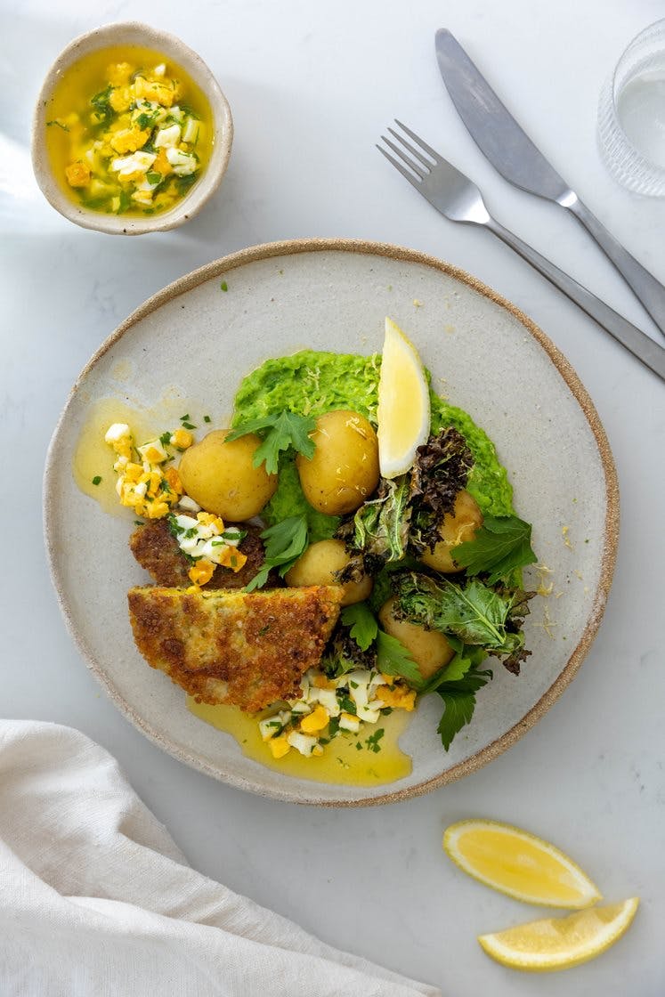 Vegetarschnitzel med kokte poteter og ertepuré servert med grønnkålchips og eggesmør