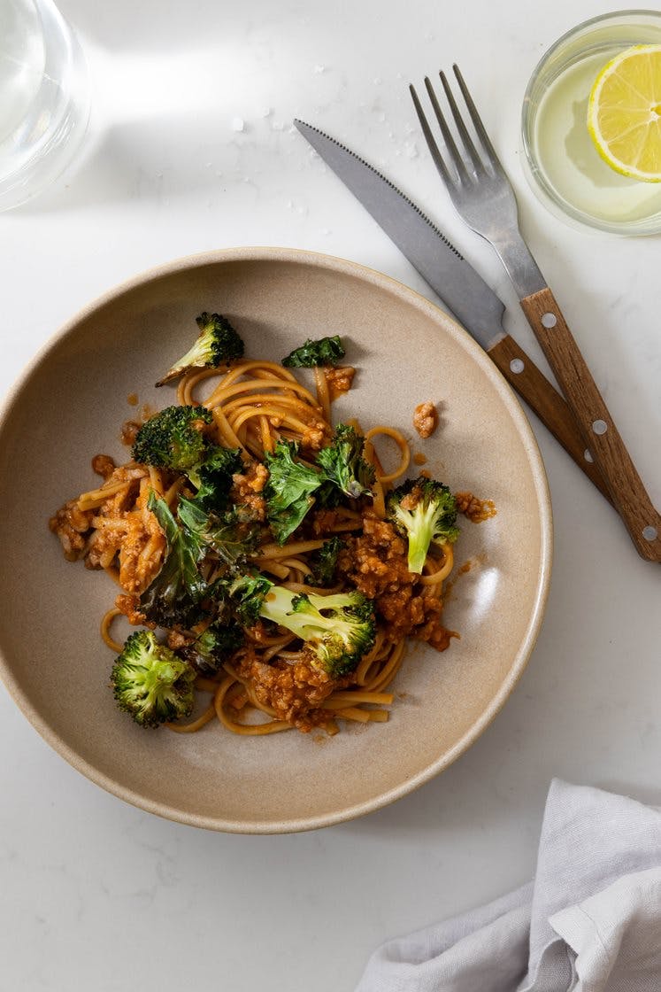 Kjøtt- og grønnsaksdeig i tomatsaus med fullkornspasta servert med bakt brokkoli og grønnkålschips