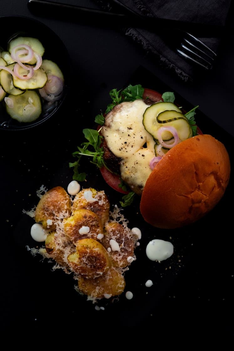 Trøffelburger med mozzarella, smashede krydderpoteter, sylteagurk, ruccola og tomat